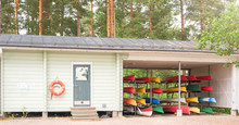 Pavilion Of Boat Station With Lifebuoy And Racks With Canoes On Sunny Spring Day