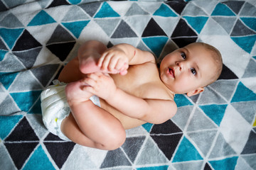 little boy age 8 months and is smiling. He wears a diaper. Health and development of children