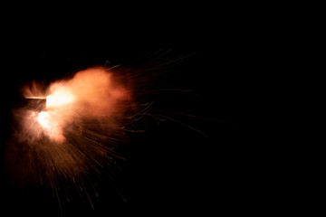 Wall Mural - A shot from a firearm on a black background, a fiery exhaust with flying sparks, flames bursting out of the pipe