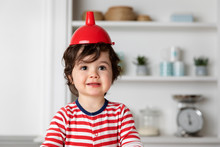 Portrait Of Funny Toddler In Kitchen Wearing Funnel On Head