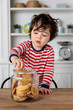 © Lisa Tichané - Young boy getting biscuits from cookie jar on kitchen table
