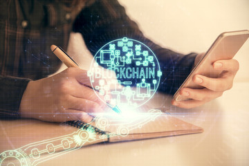 Double exposure of blockchain business sketch hologram and woman holding and using a mobile device.