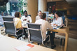 © BullRun - Confident male and female colleagues sitting at working table together discussing project in cooperation, multiracial group of corporate employees have successful productive job in brainstorming