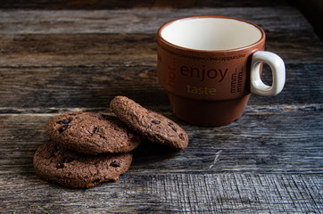 Three oatmeal cookies with cocoa, a cup for coffee on a wooden table.