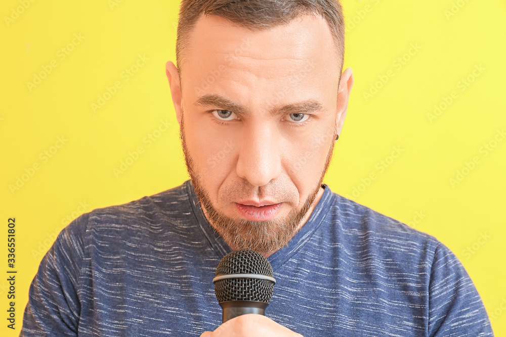 Male singer with microphone on color background