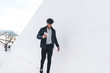 © BullRun - Trendy amused African American man using tablet while walking along urban street tunnel