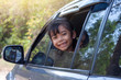 © Pannarai - Little girl enjoying the trip smile and show head out of car window on the road.