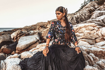 beautiful young fashionable woman on the rocks at sunset