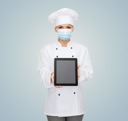 health, safety and pandemic concept - female chef, cook or baker wearing face protective medical mask for protection from virus disease with tablet pc computer