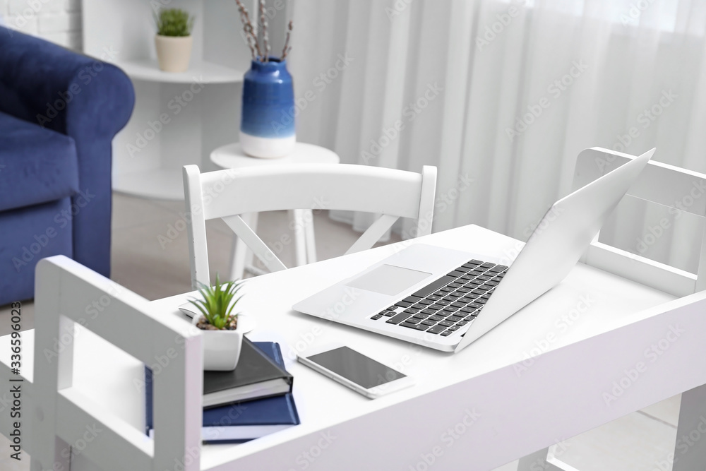 Modern laptop on workplace in room