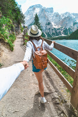 Wall Mural - follow me concept woman walking by trail around lake in mountains