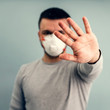 © Natalya Lys - A man is putting on a protective mask. Respiratory protection from coronavirus. Personal protective equipment for a pandemic of a viral infection. Covid-19.