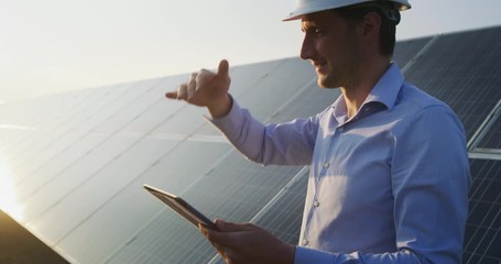 Wall Mural - an young engineer is checking with tablet an operation of sun and cleanliness on field of photovolta