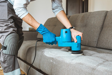 Man hands close up in in protective rubber glove, Dry cleaner's employee removing dirt from furniture in flat, closeup, vacuum clean sofa with professional equipment.