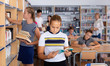 © JackF - Schoolgirl standing with book before lesson in school library, reading textbook