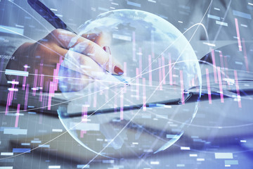 Multi exposure of woman's hands making notes with forex graph hologram. Concept stock market analysis.