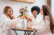 © unai - Session in beauty salon. Three young models in white coats sitting after treatment. Blonde girl, brunette girl and girl of Caribbean American origin with afro hair