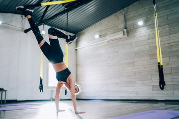 Wall Mural - Young fit female athlete raising leg while standing on hands