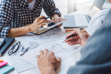 engineer Hand Drawing Plan On Blue Print with architect equipment discussing the floor plans over blueprint architectural plans at table in a modern office.