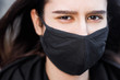 © Nickolay - Young woman wearing face mask. Handsome woman in black hoodie wear black medical mask. Pandemic coronavirus covid-19 quarantine period concept.