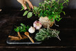 © Matt & Lena - Various fresh herbs and spices on a table with person picking a leaf