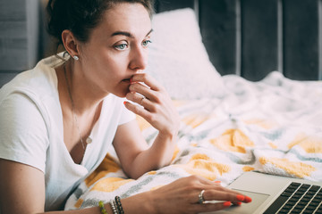 Serious young girl works from home online during a quarantine virus outbreak. Solves work tasks on a laptop in his room. near the bed. Close-up. Place for text. Stay at home concept. Copy space