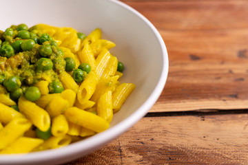 Wall Mural - Creamy paste with green peas and saffron. Italian penne pasta for lunch. Summer food, fast lunch.