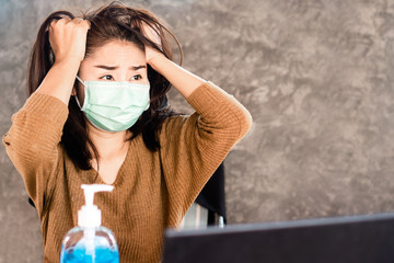 stress Asian woman wearing protective mask angry and get depressed during covid-19 virus outbreak ,quarantine and home lockdown sitting with alcohol gel on desk