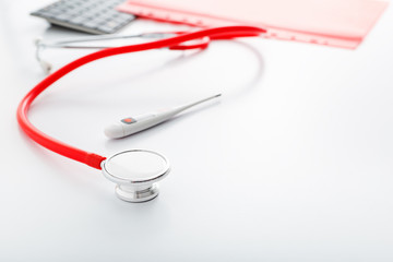 Medical thermometer red stethoscope on white table. Doctors professional equipment on workspace. Healthcare medical concept. Doctor appointment. Coronovirus Covid-19 prevention