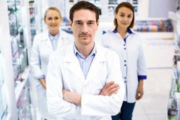 Wall Mural - Serious three young pharmacists working in drugstore