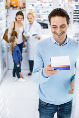 Wall Mural - Joyful happy man examining pills in a drugstore