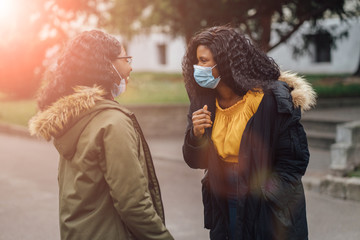 How virus affects a human. Rules. Bacteria. Safety. Protect. Medicine. Bacteria. Hygiene. Avoid touching concept. Portrait of two nigerian women in medical mask walking outdoor in city street.