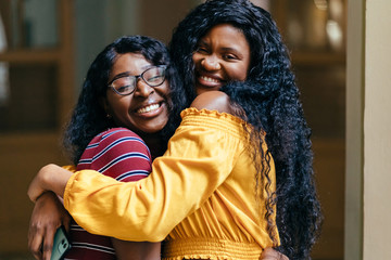 Portrait of two female nigerian students meets in dark university interior. African woman in bright cilor clothes