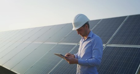 Wall Mural - an young engineer is checking with tablet an operation of sun and cleanliness on field of photovolta