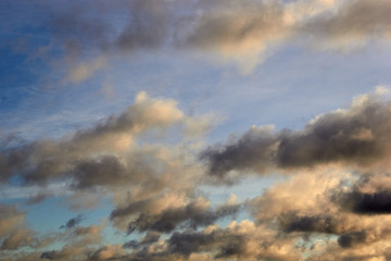 low-floating Cumulus clouds at dawn against a blue sky