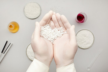 Wall Mural - The laboratory assistant holds a handful of white plastic polymer