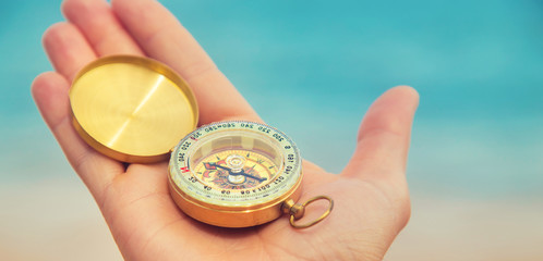 Compass on the background of the sea and the beach. Selective focus.