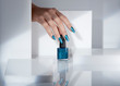 © Will Anderson - Close up of woman's hand holding blue nail polish bottle