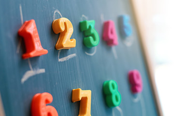 Learning numbers on a blackboard with colorful magnets and handwriting on blackboard during homeschooling at quarantine