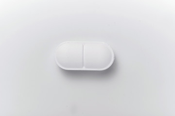 Close-up of white pill isolated on white background.