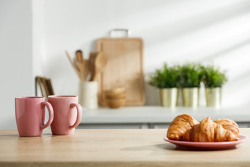 Wall Mural - Wooden table in a sunny kitchen in the morning light during breakfast