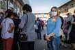 © Adil - young woman standing in line at the market. in a protective mask during a coronovirus pandemic. dressed in a blue sweater and jeans. blonde with gathered hair. Coronavirus pandemic effects.