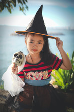 Portrait Of Girl Wearing Witch Hat Holding Skull