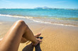 Long slim young woman legs relaxing lying down and sunbathing on sand tropical beach under hot sun in summer. Skincare, sun aging protection and sea travel concept.