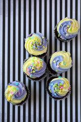 Wall Mural - Top view of yellow and purple easter cupcake on lined background