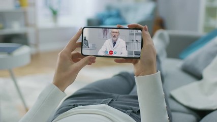Young Girl Sick at Home Using Smartphone to Talk to Her Doctor via Video Conference Medical App. Woman Has Conversation with Physician, Using Online Video Chat Application. Close-up POV View
