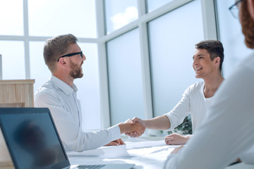 Wall Mural - business people shaking hands in a bright office.