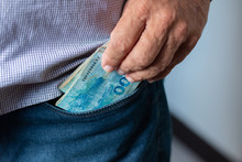 Man Putting Brazilian Money Notes In His Pants Pocket. Selective Focus.