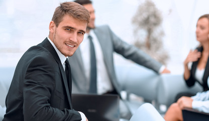 Sticker - successful handsome businessman sitting at a work Desk on blurred background