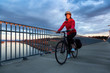 © edb3_16 - Caucasian Woman riding a Bicycle on a path at Port Mann Bridge during vibrant Sunset. Taken in Surrey, Vancouver, British Columbia, Canada.